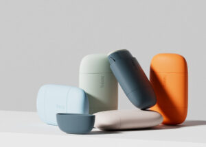 Fussy Deodorant re-fillable cases in pale blue, pale green, orange, white and midnight blue arranged on a table