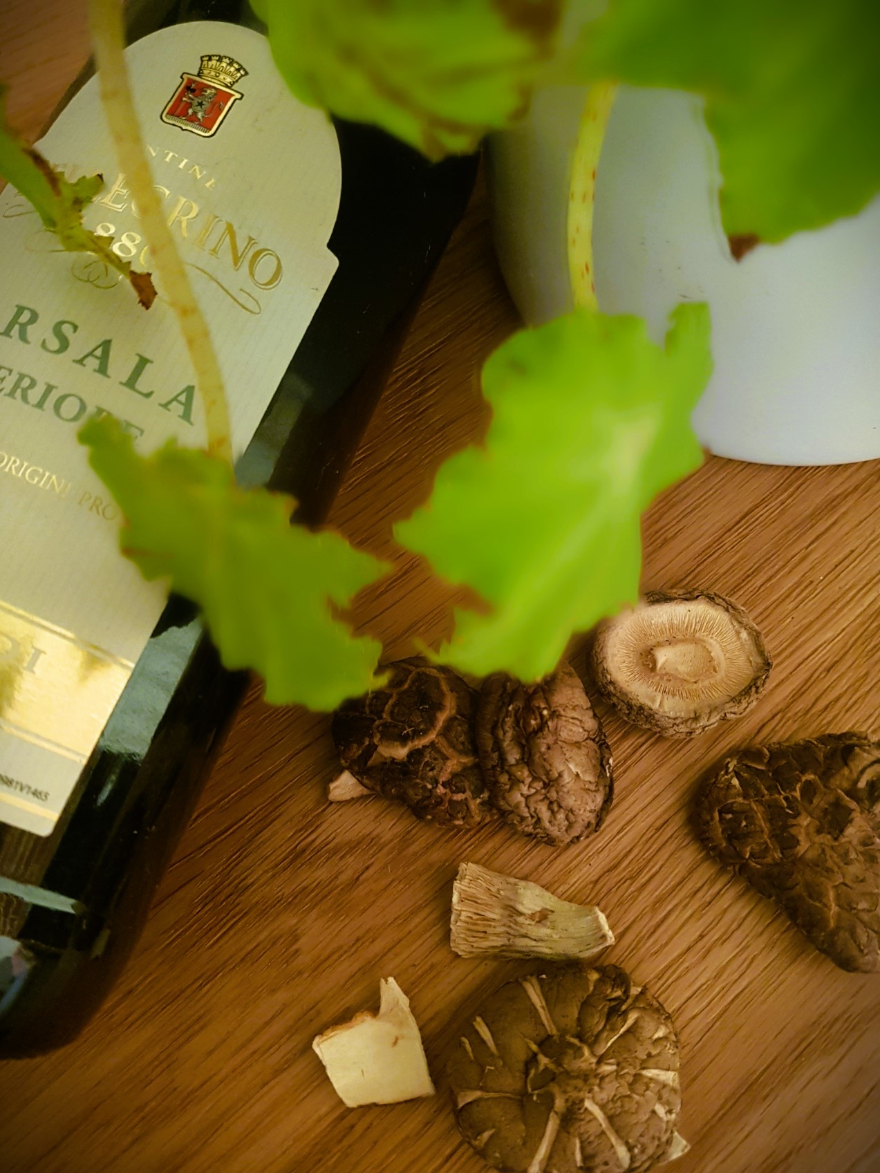 Bottle of Marsala Wine with dried shiitake and mixed mushrooms scattered beneath a plant