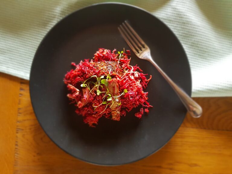 clay pot beetroot noodles with smoked tofu on a black dinner plate, to illustrate this review of East by Meera Sodha