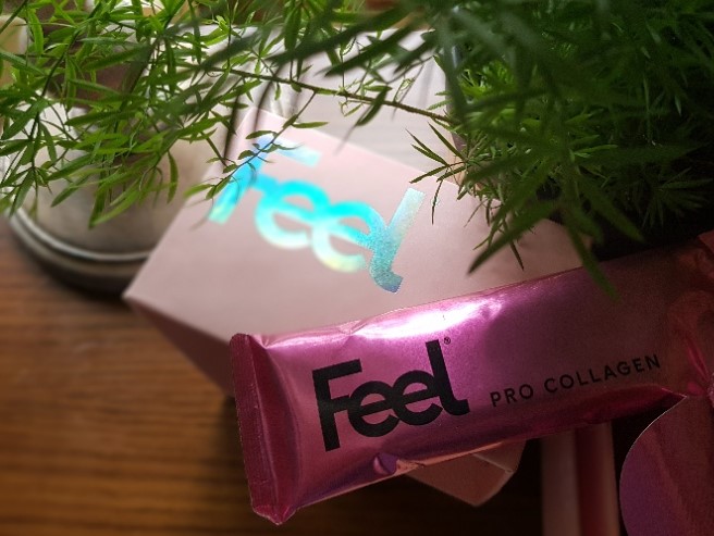 Image of product being described in this Feel Pro Collagen Gel Review including a bright pink metallic sachet of the gel, viewed through the leaves of an asparagus fern