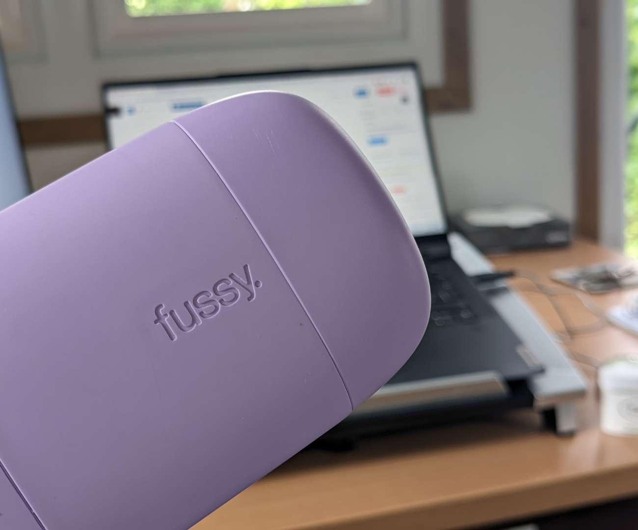 Lilac coloured plastic Fussy refillable natural deodorant case, in front of a laptop to illustrate this Does Fussy natural Deodorant work blog
