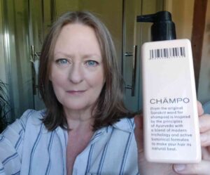 Vegan Mum holding a bottle of Champo Pitta hair conditioner in a bathroom setting